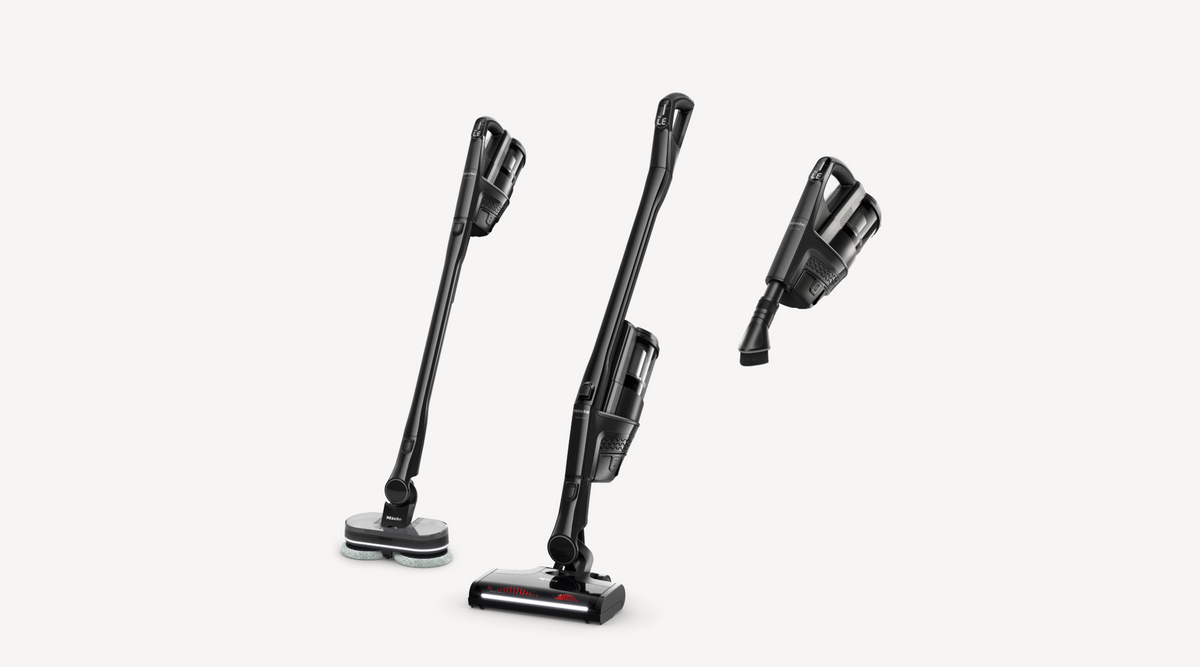 Three views of a cordless stick vacuum cleaner in black and dark gray, shown on a clean light gray background.