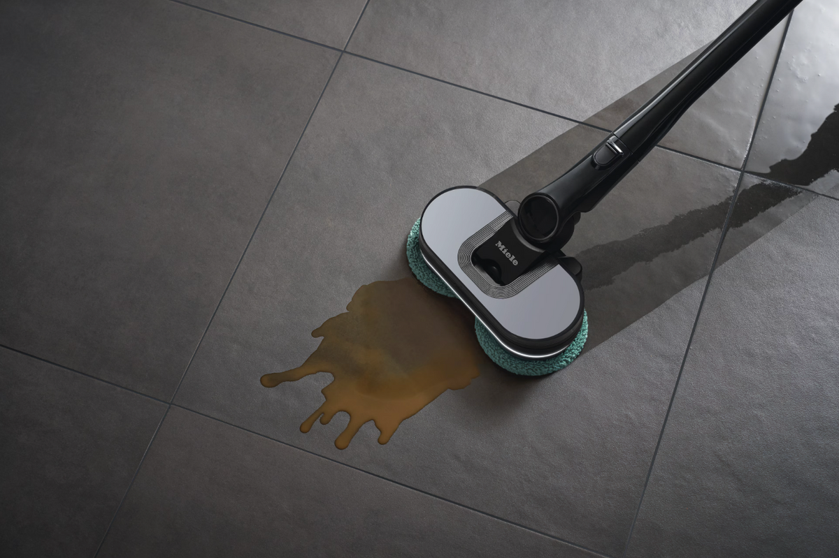 Cleaning device cleaning a spill on a tiled floor