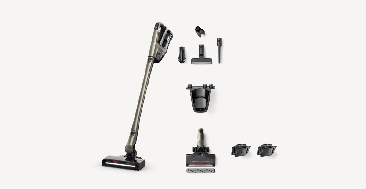 A cordless stick vacuum cleaner shown with multiple attachments and accessories arranged neatly on a light gray background.
